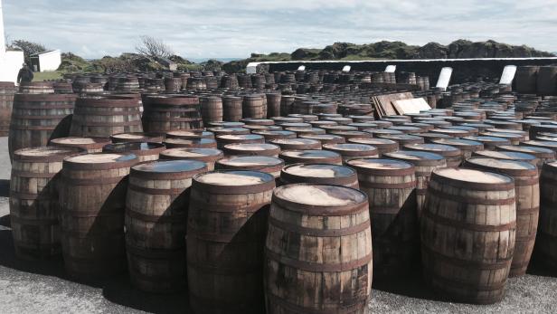 Viele Whiskyfässer stehen im Freien auf einem Lagerplatz.