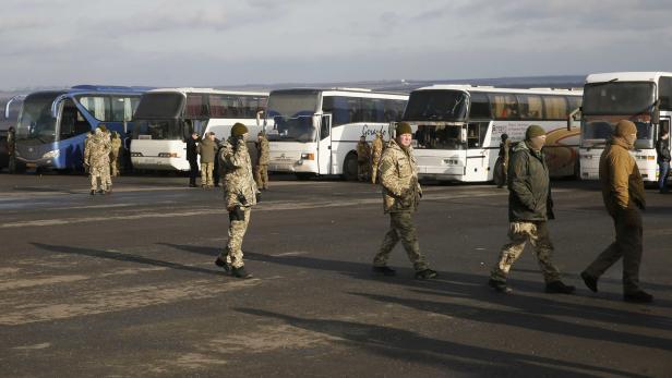 Ukrainische Soldaten vor Bussen, die Gefangene transportieren