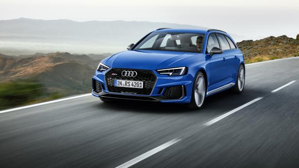 Ein blauer Audi RS 4 Avant fährt auf einer Straße in bergigem Gelände.