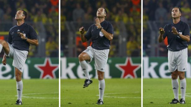 Ein Fußballschiedsrichter gestikuliert auf dem Spielfeld.