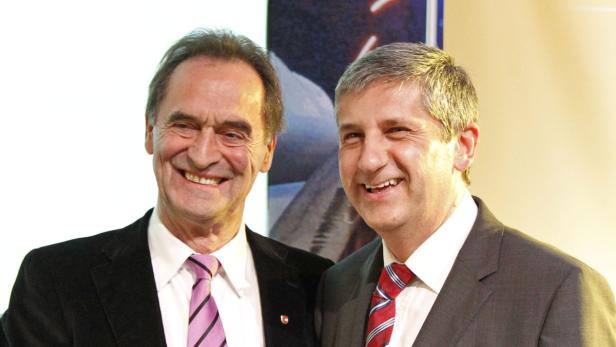 Zwei lächelnde Männer in Anzügen stehen nebeneinander.