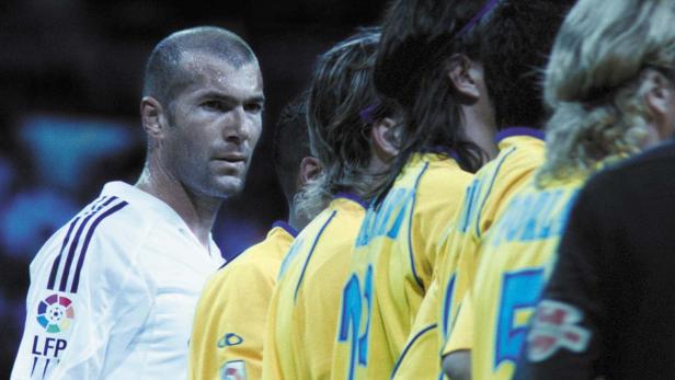 Zinedine Zidane im weißen Trikot neben einer Reihe von Fußballspielern in gelben Trikots.