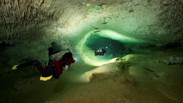 Höhlentaucher tauchen immer weiter in die Höhle hinein.
