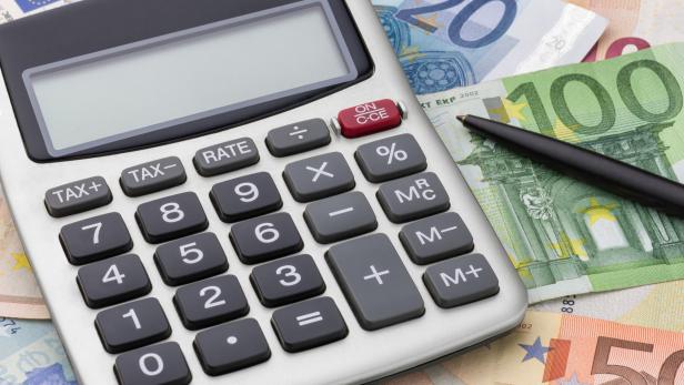 Ein Taschenrechner liegt auf einem Stapel von Euroscheinen, daneben ein Stift.