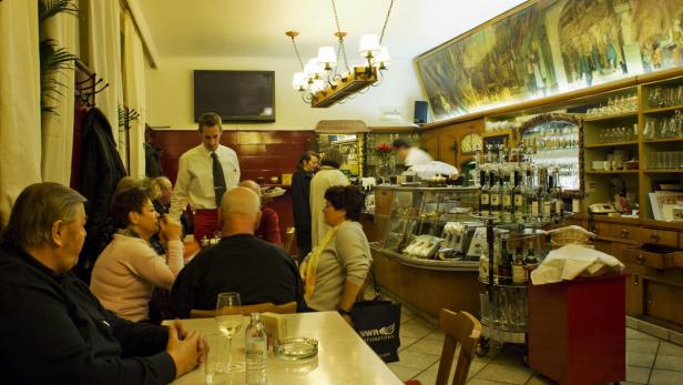 Gäste sitzen in einem traditionellen Restaurant, ein Kellner bedient sie.