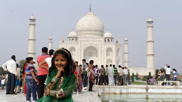 Ein junges Mädchen posiert vor dem Taj Mahal in Indien.