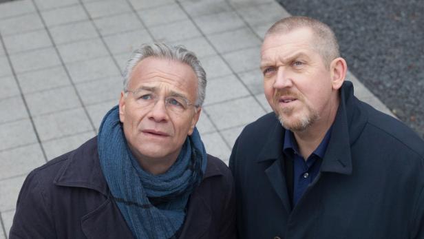 Zwei Männer in Winterkleidung schauen nach oben.