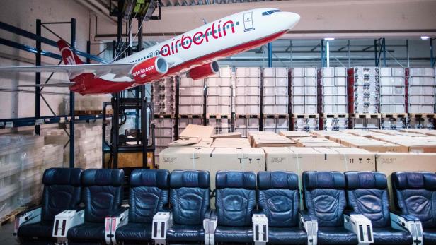 Ein Air Berlin-Flugzeugmodell hängt über Flugzeugsitzen und Kisten in einem Lagerhaus.