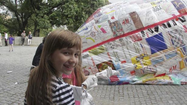 Ein Mädchen lächelt vor einem großen, mit Logos beklebten Objekt.