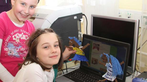Zwei Mädchen stehen vor einem Laptop mit Pferde-Animationen.