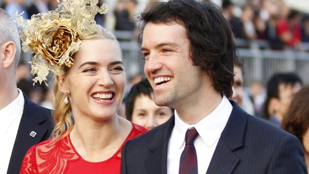 Kate Winslet mit Hut und ihr Ehemann Ned Rocknroll lächeln in die Kamera.