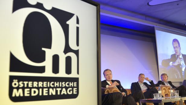 Drei Männer sitzen auf einer Bühne während der Österreichischen Medientage.
