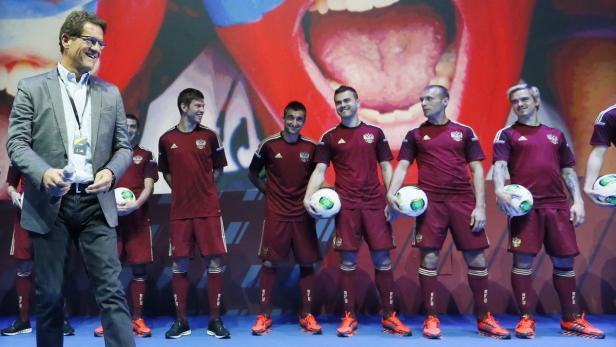 Ein Mann mit Mikrofon steht vor einer Gruppe russischer Fußballspieler mit Bällen.