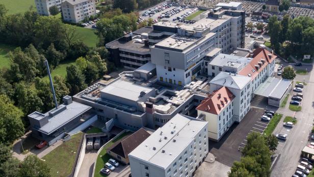 Luftaufnahme eines großen Krankenhauses mit Parkplätzen und umliegenden Grünflächen.