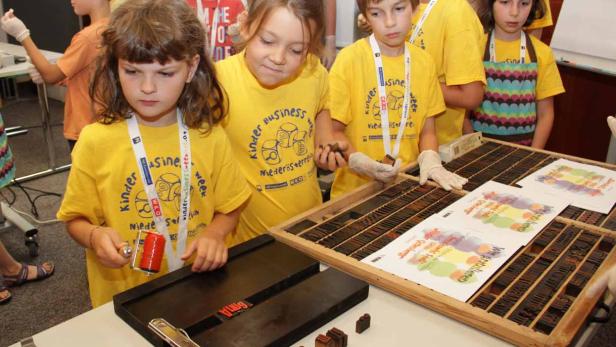 Kinder bedrucken Papier mit Stempeln während der Kinder Business Week.