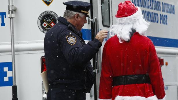 Ein New Yorker Polizist spricht mit einer Person, die als Weihnachtsmann verkleidet ist.