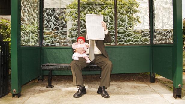 Businessman holding baby at bus stop