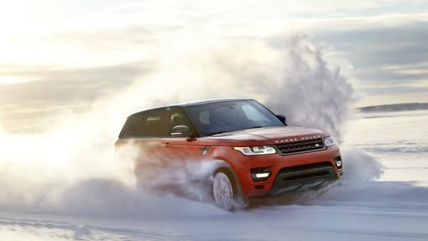 Ein roter Range Rover fährt durch den Schnee.