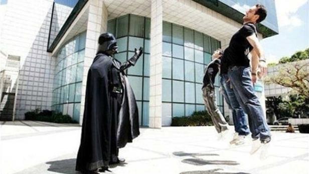 Darth Vader scheint seine Macht auf drei schwebende Personen vor einem Gebäude anzuwenden.