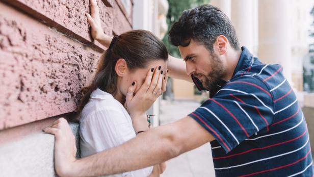 Ein Mann tröstet eine weinende Frau, die ihr Gesicht in ihren Händen verbirgt.