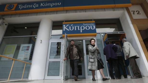People leave a Bank of Cyprus branch in Athens
