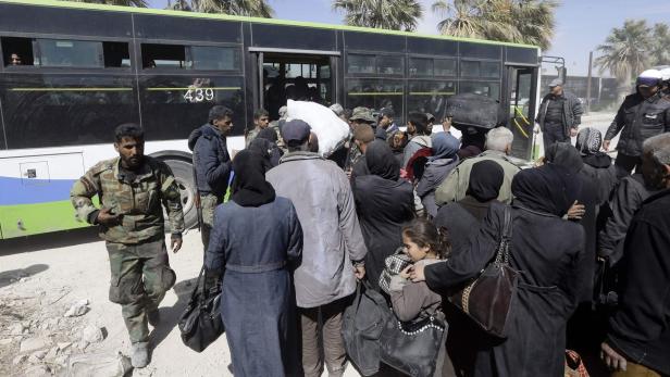 Syrian civilians, evacuated from rebel-held areas in the Eastern Ghouta, gather at a school in the regime-controlled Hosh Nasri, on the northeastern outskirts of the capital Damascus on March 16, 2018, ahead of being relocated to other areas. On the edge of Ghouta, a sprawling semi-rural area within mortar range of central Damascus, hundreds of civilians were still streaming out of destroyed towns, carrying scant belongings in bags and bundles. / AFP PHOTO / LOUAI BESHARA