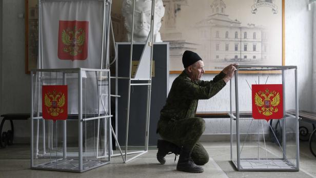 A worker assembles and places ballot boxes and voting booths at a polling station, located at a cadet school, ahead of the upcoming presidential election in the city of Stavropol, Russia March 16, 2018. REUTERS/Eduard Korniyenko