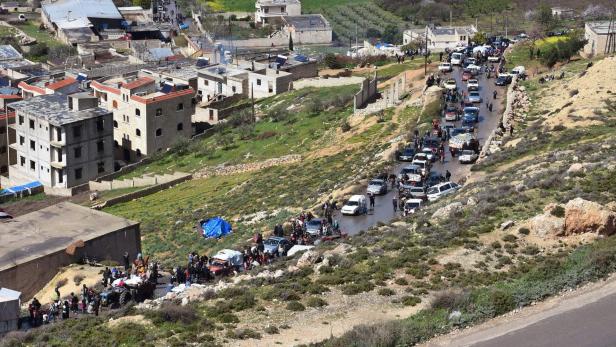 Civilians fleeing the city of Afrin in northern Syria walk at the mountainous road of al-Ahlam while heading towards the check point in az-Ziyarah, in the government-controlled part of the northern Aleppo province, on March 16, 2018. A Turkish-led offensive to capture the Kurdish-majority enclave of Afrin in northern Syria has forced 30,000 civilians from its main city in 24 hours, a monitor said yesterday. / AFP PHOTO / George OURFALIAN