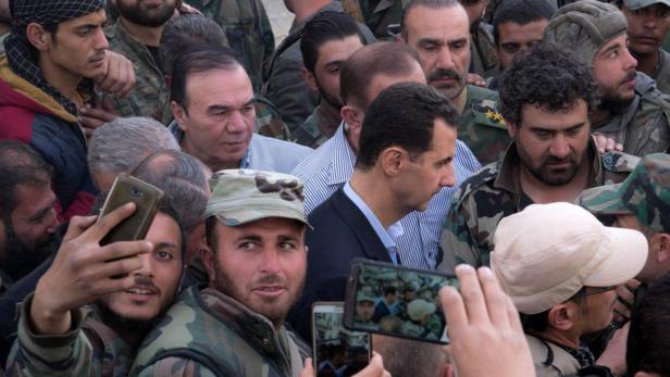 Syrian army soldiers take pictures with their mobile phones of Syrian President Bashar al-Assad in eastern Ghouta, Syria, March 18, 2018. SANA/Handout via REUTERS ATTENTION EDITORS - THIS IMAGE HAS BEEN SUPPLIED BY A THIRD PARTY. REUTERS IS UNABLE TO INDEPENDENTLY VERIFY THIS IMAGE.