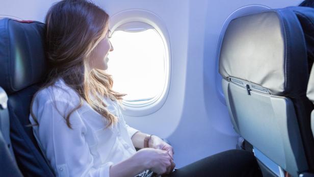 Young woman looks out aircraft window during flight