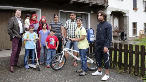 Eine Gruppe von Menschen unterschiedlichen Alters steht vor einem Haus.