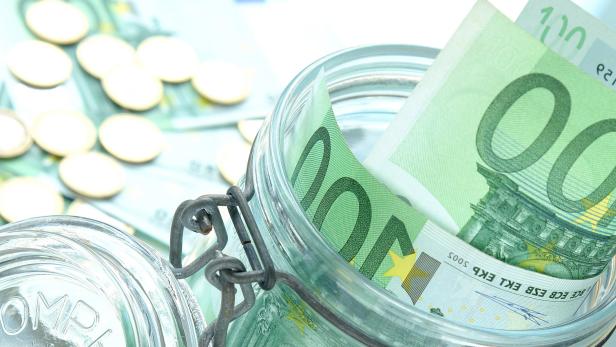 Einmachglas gefüllt mit 100-Euro-Scheinen und Euro-Münzen.