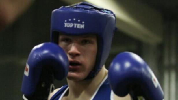 Ein junger Boxer mit blauem Kopfschutz und Boxhandschuhen.