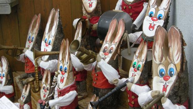 Eine Gruppe von Hasenfiguren aus Holz spielt verschiedene Musikinstrumente.