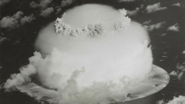 Handout of a mushroom cloud rises with ships below during Operation Crossroads nuclear weapons test on Bikini Atoll