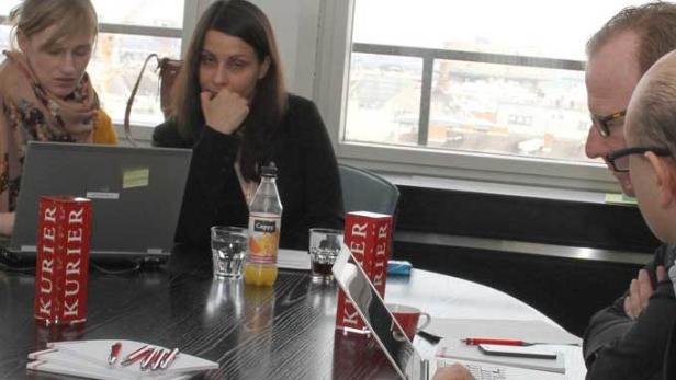 Mehrere Personen sitzen an einem Tisch mit Getränken und Laptops.