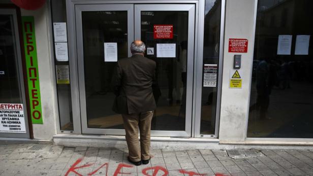 A depositor waits to enter a Laiki Bank branch in Nicosia March 28, 2013. Cypriots queued calmly at banks as they reopened on Thursday under tight controls imposed on transactions to prevent a run on deposits after the government was forced to accept a stringent EU rescue package to avert bankruptcy. The graffiti on the pavement reads, &quot;Thieves&quot;. REUTERS/Yannis Behrakis (CYPRUS - Tags: BUSINESS POLITICS TPX IMAGES OF THE DAY)