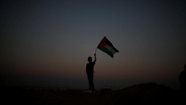 Boy waves a Palestinian flag, at the Israel-Gaza border, during clashes with Israeli troops, at a protest where Palestinians demand the right to return to their homeland, east of Gaza City