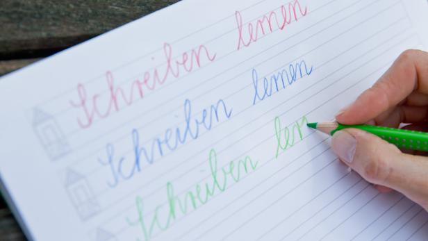 ARCHIV - ILLUSTRATION - Auf einem Schulheft ist in den Farben rot, blau und grün &quot;Schreiben lernen&quot; am 12.06.2014 in Nürnberg (Bayern) zu lesen. Der Umgang mit dem Smartphone oder dem Tablet ihrer Eltern bereitet den meisten Grundschülern keine Probleme. Dagegen kämpfen einige von ihnen in der Schule mit dem großen G oder dem kleinen h. Ist die Schreibschrift überhaupt noch zeitgemäß? Foto: Daniel Karmann/dpa (zu dpa-Korr &quot;Schreibschrift vom Aussterben bedroht - Experten fordern Rettung&quot; vom 18.06.2014) +++(c) dpa - Bildfunk+++