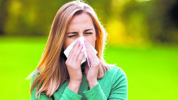 Woman with allergy symptom blowing nose