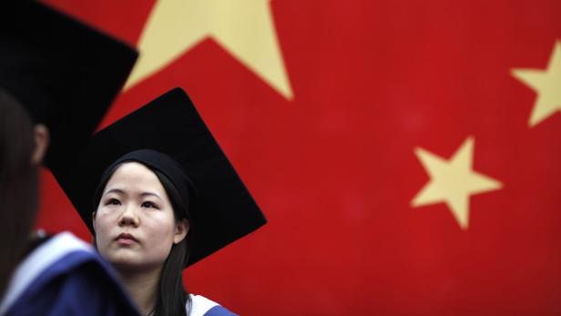 Eine junge Frau mit Doktorhut vor der chinesischen Flagge.