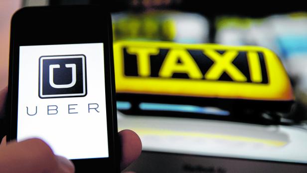 Ein Smartphone mit dem Uber-Logo vor einem gelben Taxischild.
