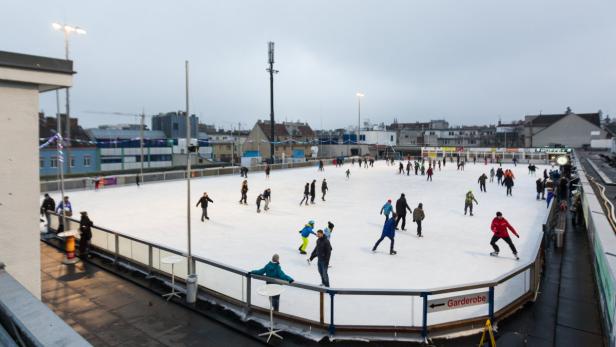 Viele Menschen laufen auf einer Eisbahn im Freien Schlittschuh.