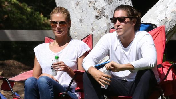 Heidi Klum und Tom Kaulitz sitzen in Campingstühlen und halten Getränke.