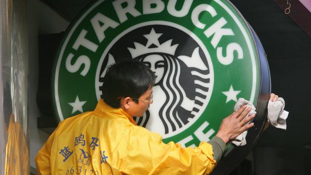 Ein Mann reinigt ein Starbucks-Schild mit einem Tuch.