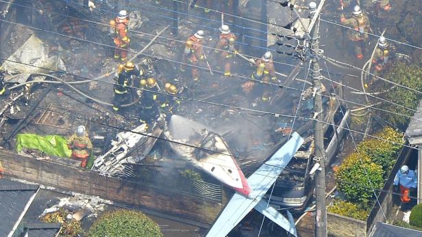 Feuerwehrleute löschen ein Flugzeugwrack in einem Wohngebiet.
