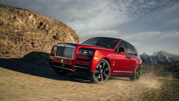 Ein roter Rolls-Royce Cullinan fährt auf einer unbefestigten Straße.