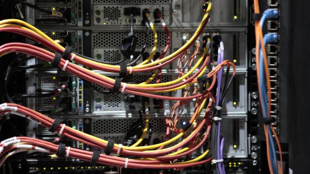 Ein Serverschrank mit vielen bunten Kabeln und blinkenden Lichtern.