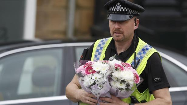 Ein Polizist bringt Blumen zur Stelle, an der Jo Cox ermordert wurde