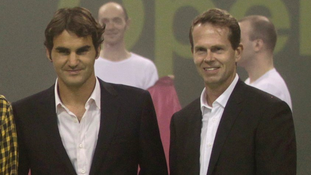 Roger Federer und ein weiterer Mann in Anzügen posieren für ein Foto.